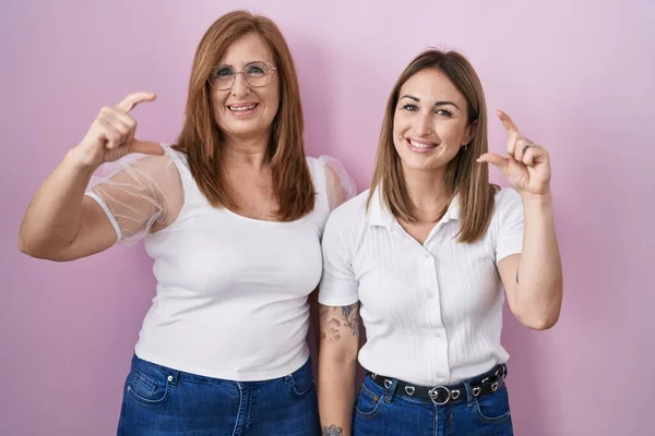 아메리카 사람들의 어머니와 티셔츠를 분홍색 배경에 미소를 지으며 몸짓으로 손가락 — 스톡 사진