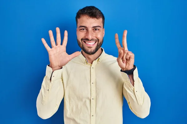 自信と幸せ笑顔ながら青の背景を示すと指番号7で指摘しながらハンサムなヒスパニック系の男 — ストック写真