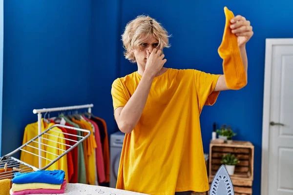 Young Blond Man Holding Dirty Sock Laundry Room — Stock fotografie