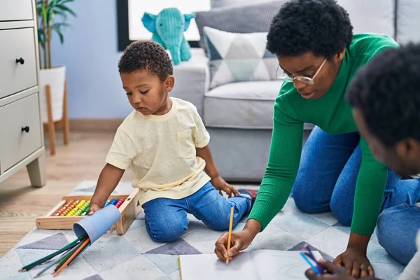 stock image African american family drawing on notebook sitting on floor at home