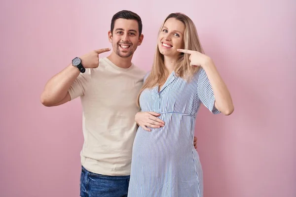 Casal Jovem Esperando Bebê Sobre Fundo Rosa Sorrindo Alegre Mostrando — Fotografia de Stock