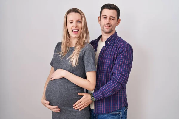 Jong Paar Verwacht Een Baby Staan Witte Achtergrond Knipperen Kijken — Stockfoto