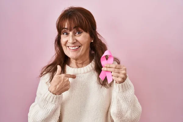 中年ヒスパニック女性保持ピンク癌リボン指差し指へ一人の自己笑顔幸せと誇り — ストック写真