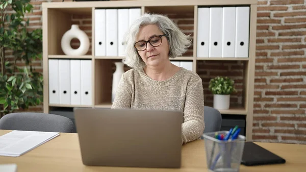 使用笔记本电脑在办公室工作的中年妇女与灰发商人 — 图库照片