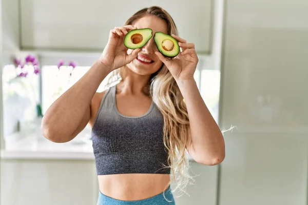 Young Woman Smiling Confident Holding Two Middle Avocado Eyes Kitchen — ストック写真