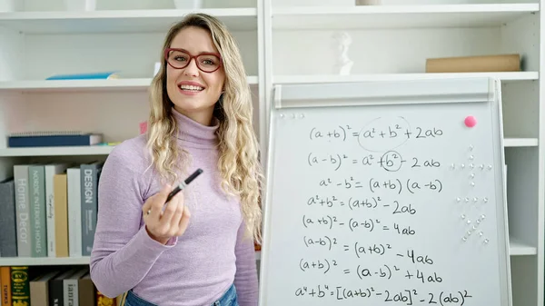 Young blonde woman teacher teaching maths lesson at classroom