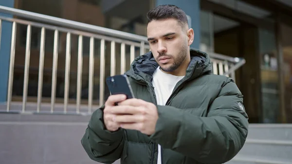Joven Hispano Usando Smartphone Con Expresión Seria Calle —  Fotos de Stock