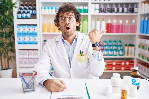 Hispanic Young Man Working Pharmacy Drugstore Surprised Pointing Hand Finger — Stock Photo, Image