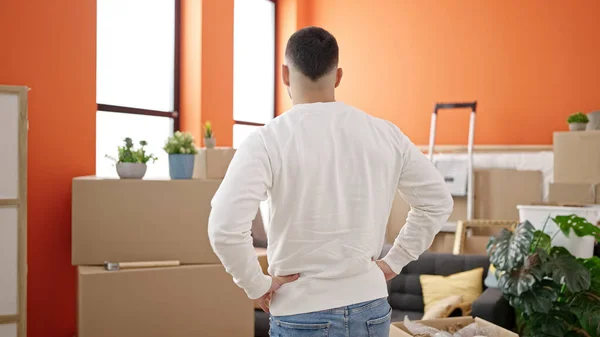 Young hispanic man standing on back view at new home