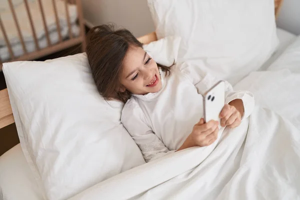 Adorable Hispanic Girl Using Smartphone Lying Bed Bedroom — Fotografia de Stock