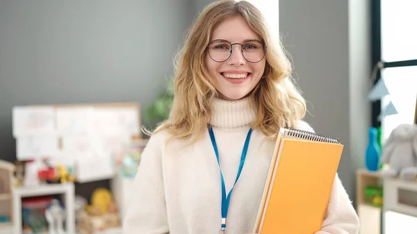 Young Blonde Woman Preschool Teacher Smiling Confident Holding Books Kindergarten — Stockfoto