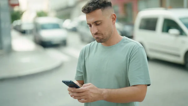 ストリートで真剣な表情のスマートフォンを使っている若いヒスパニック系の男 — ストック写真