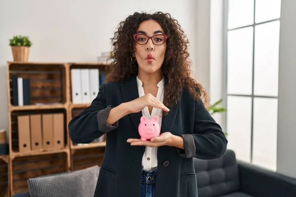 Young Hispanic Woman Holding Piggy Bank Making Fish Face Mouth — Stock Photo, Image