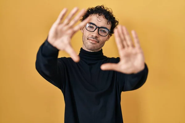 Hispanic Man Standing Yellow Background Doing Frame Using Hands Palms — Φωτογραφία Αρχείου