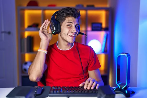 Jovem Hispânico Jogando Videogames Sorrindo Com Mão Sobre Ouvido Ouvindo — Fotografia de Stock