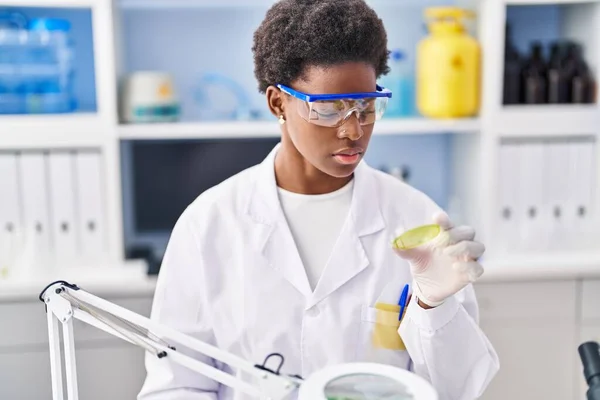研究室で虫眼鏡をかけて科学者の制服を着たアフリカ系アメリカ人女性 — ストック写真