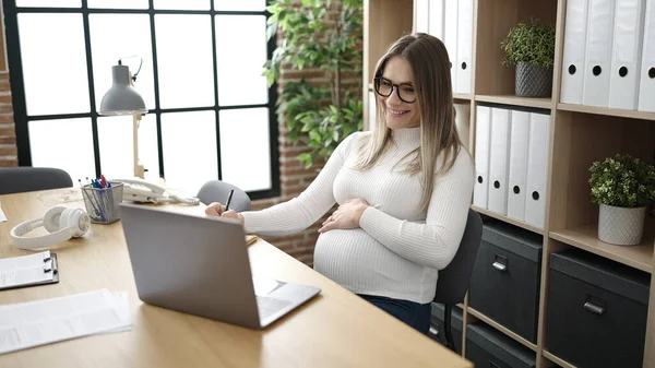 在办公室使用笔记本电脑书写的年轻怀孕女商人 — 图库照片