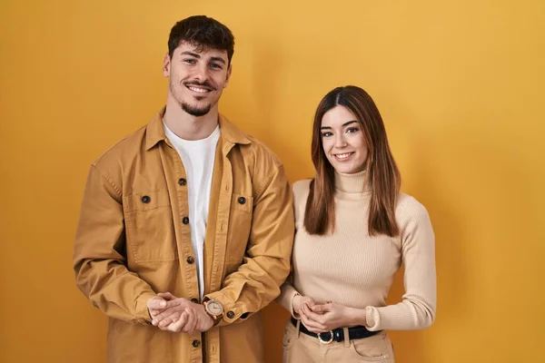 Young Hispanic Couple Standing Yellow Background Hands Together Crossed Fingers — Stock Photo, Image