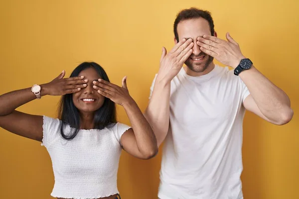 Interracial Couple Standing Yellow Background Covering Eyes Hands Smiling Cheerful — Stock Photo, Image