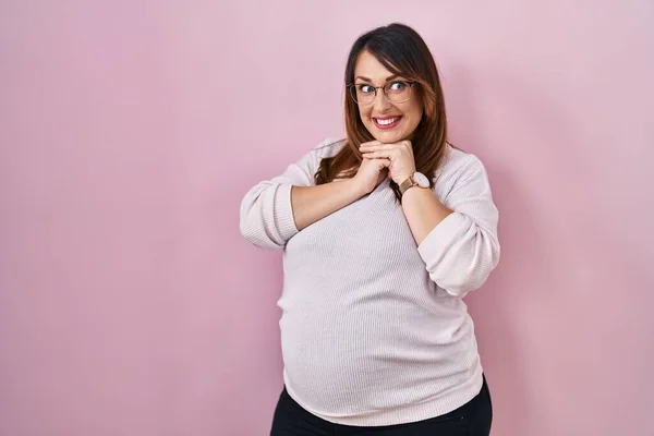 妊娠中の女性立ち上のピンクの背景笑い神経と興奮で手上の顎見ますザ側 — ストック写真