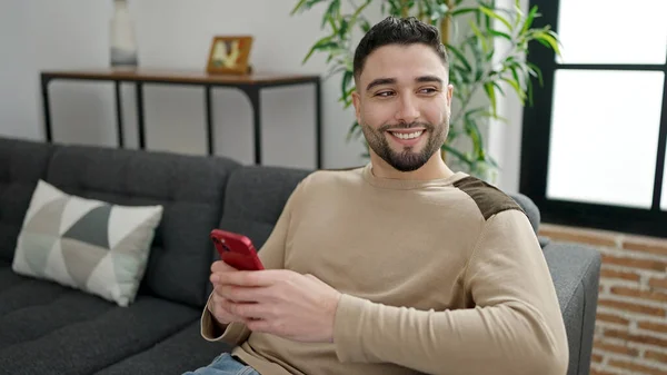 Jonge Arabier Man Met Smartphone Zittend Bank Thuis — Stockfoto
