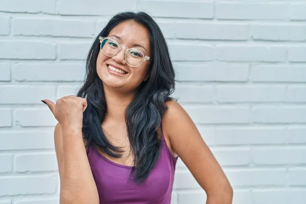 Asiático Jovem Mulher Sobre Tijolos Fundo Apontando Polegar Até Lado — Fotografia de Stock