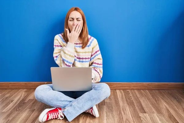 年轻女人在家里使用笔记本电脑 坐在地板上 厌烦了打呵欠 双手捂着疲惫的嘴 烦躁不安和困倦 — 图库照片