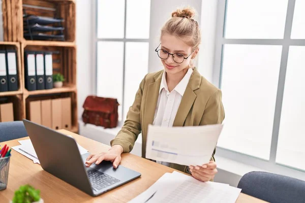若いブロンドの女性のビジネスワーカーを使用してノートパソコンの読書文書でオフィス — ストック写真