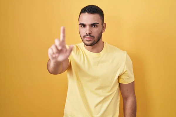 Sarı Arka Planda Dikilen Genç Spanyol Adam Parmağını Kaldırmış Kızgın — Stok fotoğraf