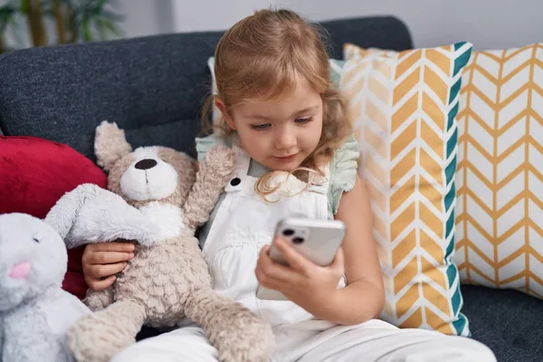 Liebenswertes Blondes Mädchen Mit Smartphone Umarmt Teddybär Hause — Stockfoto