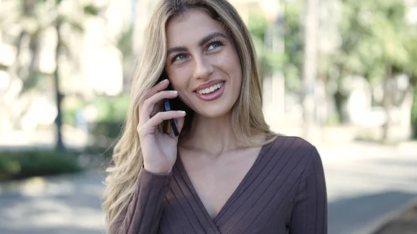 stock image Young blonde woman smiling confident talking on the smartphone at park