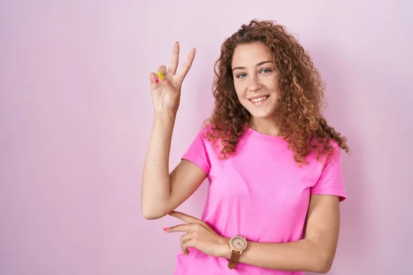 Mladá Běloška Stojící Nad Růžovým Pozadím Usmívající Kameru Ukazující Prsty — Stock fotografie
