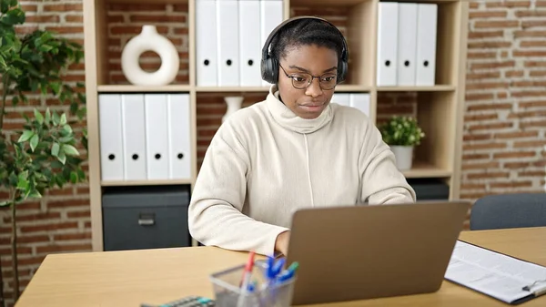 アフリカ系アメリカ人の女性ビジネスワーカーがオフィスで働くノートパソコンやヘッドフォンを使って — ストック写真