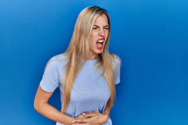 消化不良 痛みを伴う病気が体調不良のため 美しいブロンドの女性は胃の上に手で青の背景にカジュアルなTシャツを着て キャッシュ コンセプト — ストック写真