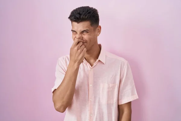 Young Hispanic Man Standing Pink Background Smelling Something Stinky Disgusting — Stockfoto