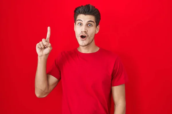 Ung Latinamerikansk Man Står Över Röd Bakgrund Pekar Finger Upp — Stockfoto
