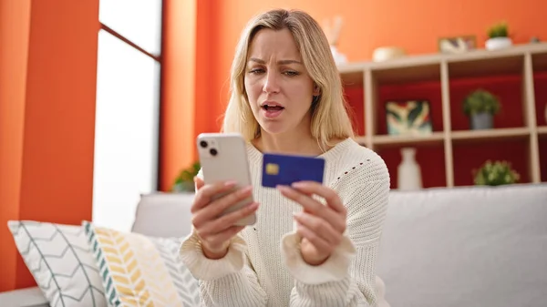 Młoda Blondynka Zakupy Smartfonem Karty Kredytowej Siedzi Kanapie Domu — Zdjęcie stockowe