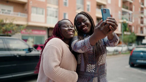 2人のアフリカ系アメリカ人の友人が自信を持って笑顔で路上でスマートフォンによる自撮り — ストック写真