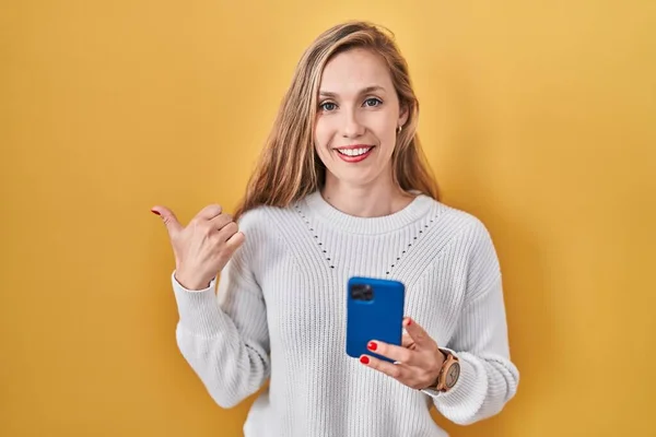 Młoda Blondynka Pomocą Smartfona Wpisując Wiadomość Wesoły Uśmiechem Twarzy Wskazując — Zdjęcie stockowe
