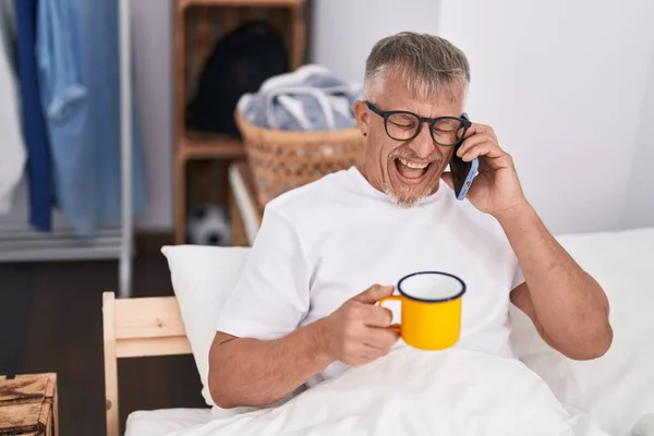 Μεσήλικας Γκριζομάλλης Που Μιλάει Στο Smartphone Πίνοντας Καφέ Στο Υπνοδωμάτιο — Φωτογραφία Αρχείου