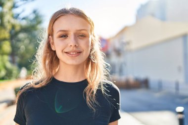 Sokakta kendine güvenen genç sarışın kadın gülümsüyor