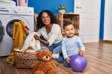 Mother and son smiling confident washing clothes at laundry room