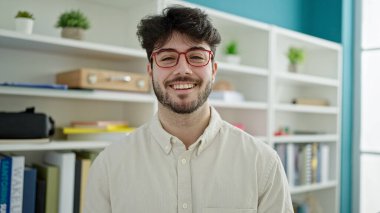 Young hispanic man student smiling confident standing at library university