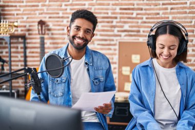 Man and woman musicians singing song playing piano at music studio