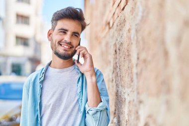 Genç İspanyol adam gülümsüyor. Kendine güveniyor. Sokakta akıllı telefondan konuşuyor.