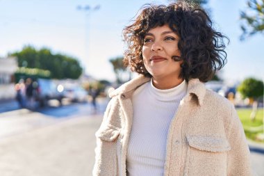 Young beautiful hispanic woman smiling confident looking to the side at street