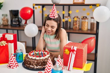 Young beautiful hispanic woman celebrating birthday sitting on table at home