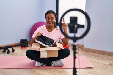 Örgülü genç Afro-Amerikalı spor salonunda akıllı telefonuyla video kaydı yapıyor. Bir fikir ya da soru işareti ile şaşırdı. 