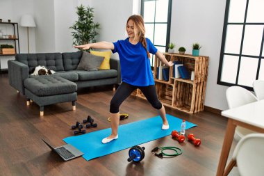 Beyaz kadın evde yoga dersi aldığından emin bir şekilde gülümsüyor.