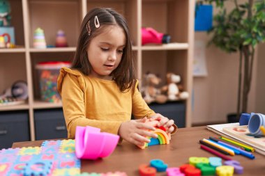 Anaokulundaki masada oturan, inşaat bloklarıyla oynayan sevimli İspanyol kız.